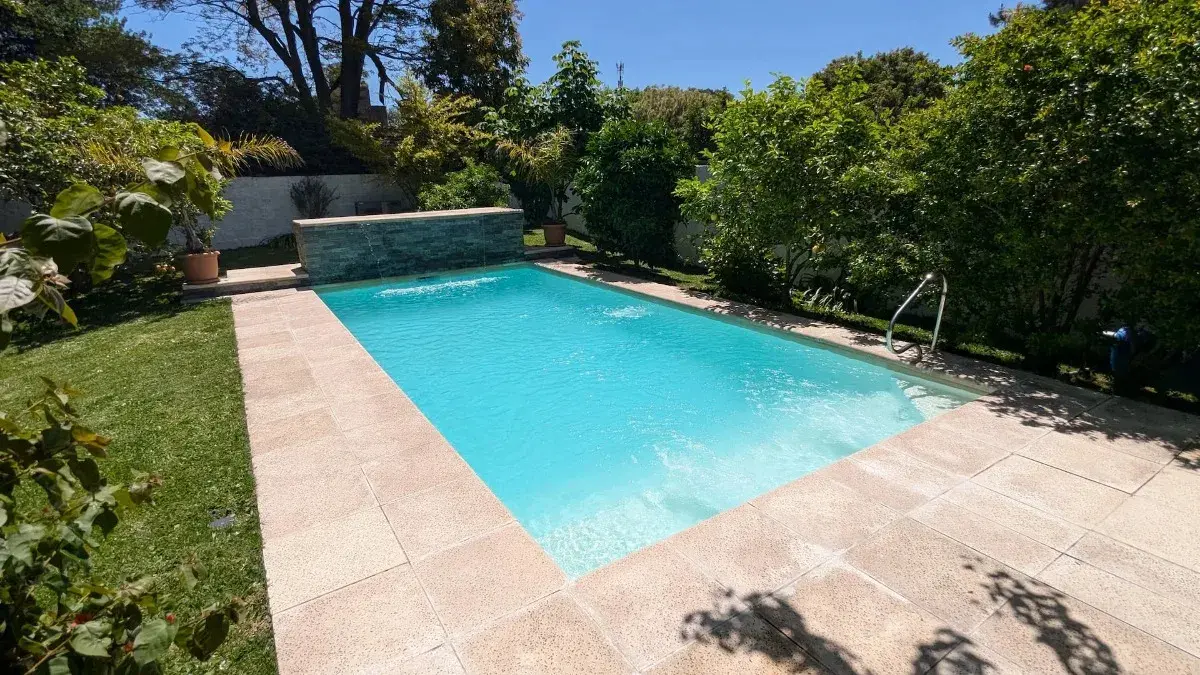 Vista de la piscina climatizada con cascada y solárium